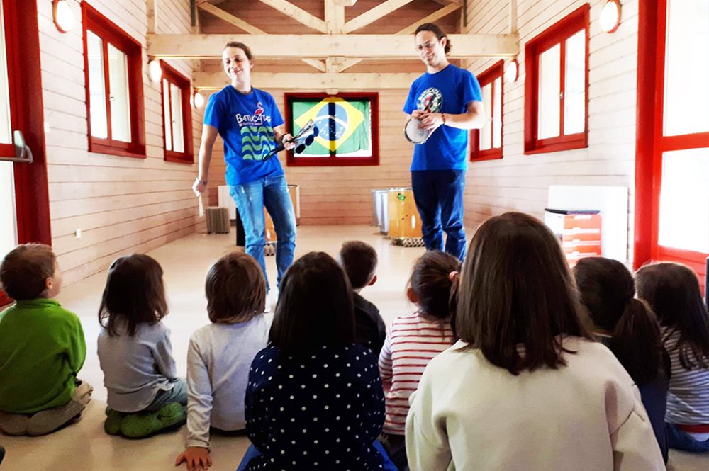 Deux musiciens font découvrir les percussions à un groupe d'enfants