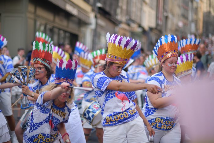 Percussionnistes en coiffes de plumes dans une rue, au milieu d'un fumigène rose