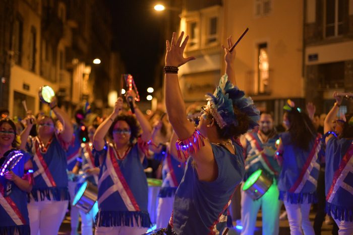 La troupe, bras levés, dans une rue éclairée à la nuit tombée
