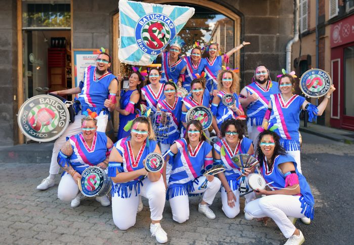 Les musiciens de BATUCATAG posent en costume bleu et blanc, tamborins et surdos en main